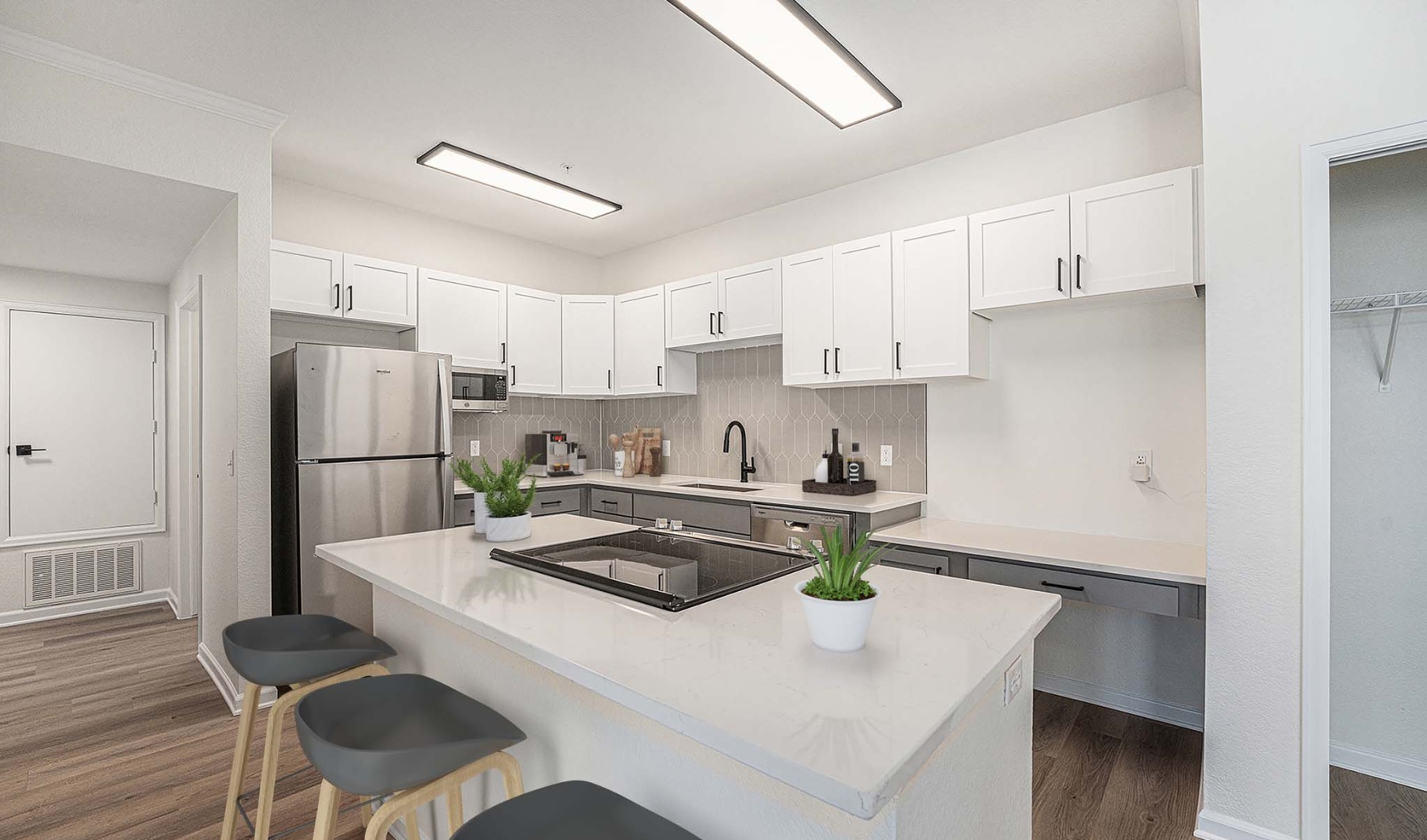 Gorgeously renovated kitchen with stainless steel appliances Open concept kitchen with white cabinets, desk, stainless steel applianes